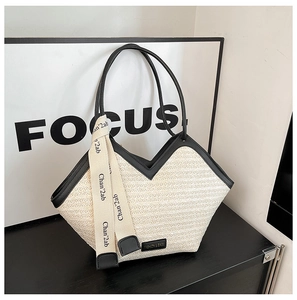 Detailed close-up of straw tote bag with black leather trim and decorative silk scarf