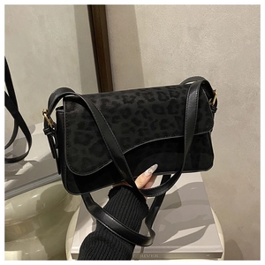 Detail of black leopard print crossbody bag with gold hardware and suede texture