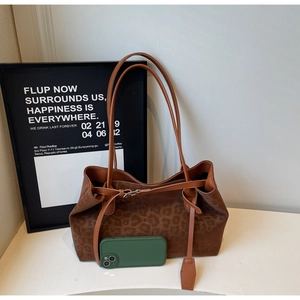 Size comparison of a leopard print tote bag next to a smartphone for scale reference