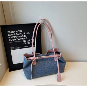 Detail of blue leopard tote bag featuring pink leather handles and metal buckle accents