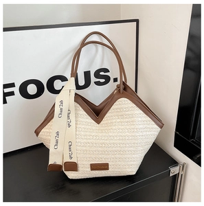 Detail of beige straw tote bag with brown leather handles and decorative brand ribbons
