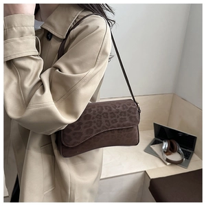 Detail of leopard print shoulder bag with matte texture on a female model in office