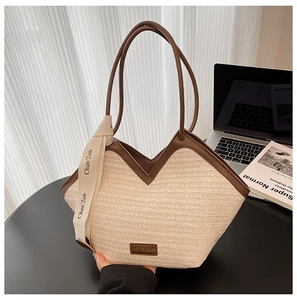 Detail of woven straw tote bag with brown leather handles and decorative silk ribbon