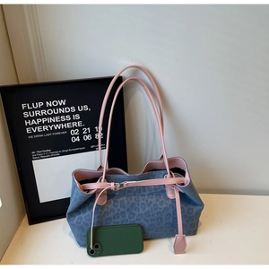 Detail view of leopard print tote bag with pink leather handles and size scale comparison