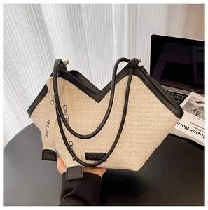 Detail of cream woven tote with V-shaped opening, black leather trim and decorative silk scarf