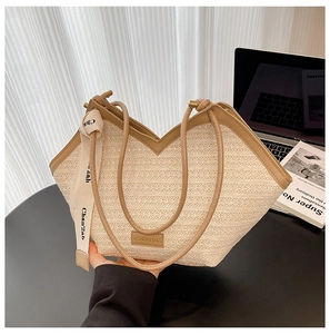 Detailed close-up of straw woven texture with brown leather handles and silk scarf detail