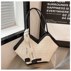 Detail of white woven straw tote bag with black leather trim and decorative ribbon strap