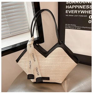 Close-up of woven tote bag with black leather trim and decorative printed ribbon