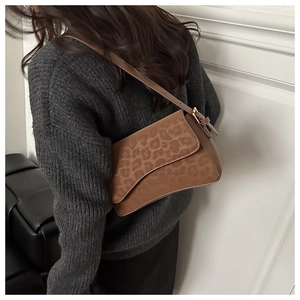 Detail of adjustable leather strap and leopard print flap on brown shoulder bag