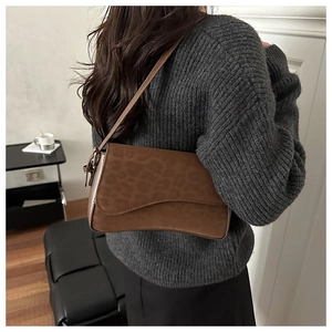 Detail of brown leather underarm bag with leopard print flap and slender shoulder strap