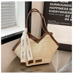 Close-up of woven straw tote bag with brown leather trim and fashion brand tag