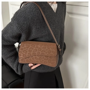 Detailed side view of vintage leopard print baguette bag worn by model in minimalist setting
