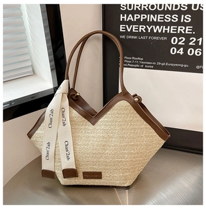 Detail view of woven straw tote bag featuring brown leather trim and decorative silk ribbon