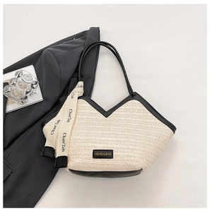 Detail of woven straw tote bag with black faux leather trim and printed silk scarf