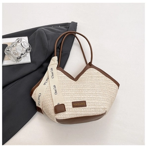 Detail of a woven straw tote bag featuring brown leather trim and fashion brand label