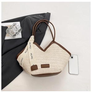Detail of the woven texture and brown leather trim on the large straw tote bag