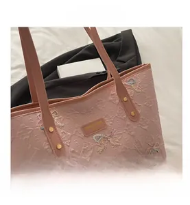 Detail of pink quilted tote bag featuring colorful bow embroidery and leather logo tag