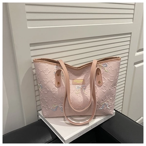 Detail of pink quilted tote bag with embroidered sequin bow and metallic brand logo