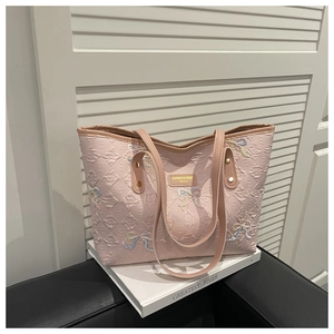 Detailed view of pink quilted tote bag with embroidered bows and reinforced leather handles