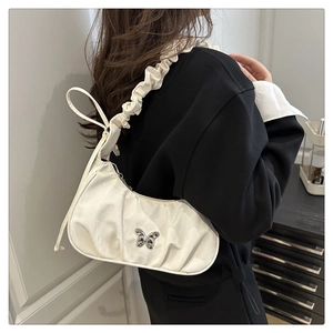 Detail of white pleated crescent bag with a silver butterfly metal buckle and ruffled strap