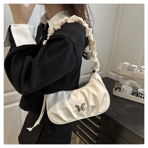 Detail of white half-moon bag with silver butterfly buckle and ruffle shoulder strap