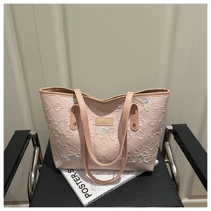 Detail view of pink quilted tote bag with embroidered bow accents and sturdy double handles