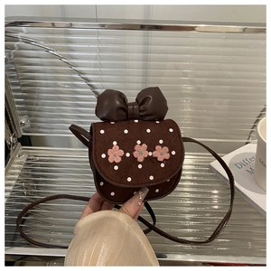 Détail d'un mini sac à bandoulière marron avec pois blancs et fleurs roses décoratives