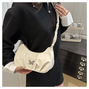 Detail of a creamy butterfly crescent bag with wrinkled strap and metallic clasp