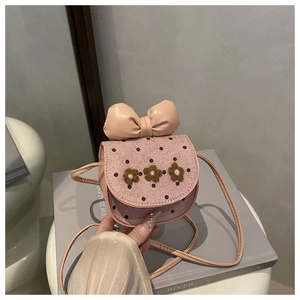Détail d'un sac bandoulière rose en velours avec accents floraux et un grand nœud en cuir
