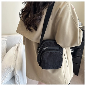 Mini sac à bandoulière vertical en velours noir avec plusieurs zips porté à l'épaule