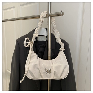 Detail of cream white pleated hobo bag featuring a silver butterfly buckle and texture
