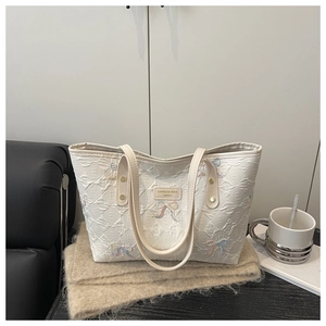 Detail of embroidered bow on quilted diamond pattern cream white tote bag