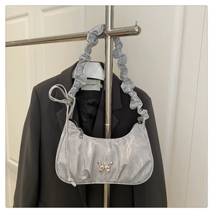 Detail view of silver pleated underarm bag with metal butterfly buckle and scrunchie strap