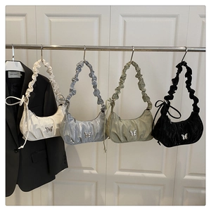 Detail showing crescent moon pleated bags in white, silver, green and black with bow buckles