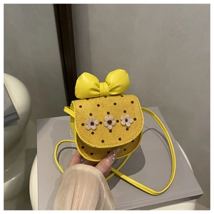 Détail d'un sac bandoulière jaune pour enfant avec grand nœud et fleurs blanches