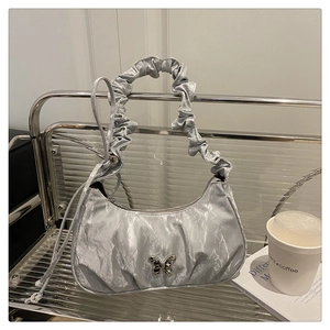 Detail of silver crescent underarm bag with butterfly metal buckle and ruched strap