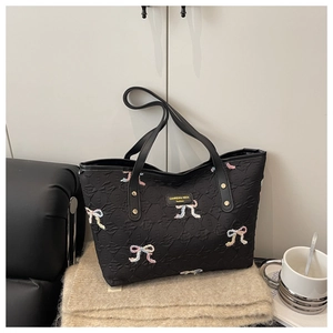 Detail of black tote bag with quilted texture and colorful embroidered bows