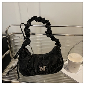 Close-up of black pleated underarm bag featuring a metallic silver butterfly clasp detail