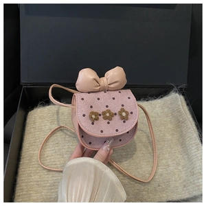 Sac bandoulière rose avec fleurs jaunes et grand nœud sur un fond en maille beige