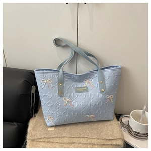 Macro detail of quilted light blue tote bag featuring sparkle bow accents and metal logo