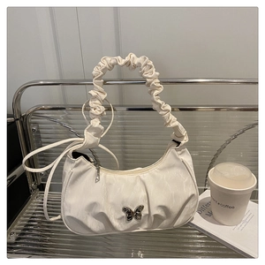 Detail of white pleated underarm bag with silver butterfly and scrunchie handle