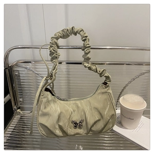 Detail of mint green crescent bag with butterfly buckle on a modern metal shelf