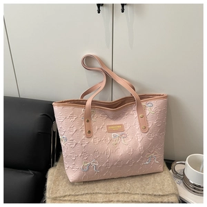 Close-up of pink tote bag with diamond lattice pattern and embroidered bow details