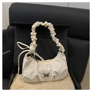 Close-up of white ruched shoulder bag featuring a decorative butterfly metal buckle