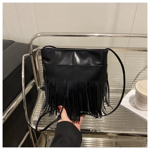 Close-up of black fringe bucket bag with dense tassels and slim leather shoulder strap