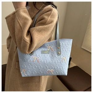 Detail of light blue tote bag with embossed textures and sequin bow accents