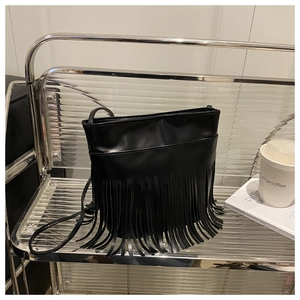 Detail of black fringe shoulder bag with bohemian tassels and smooth leather texture