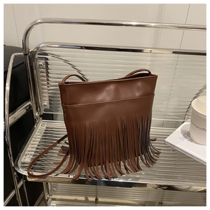 Close-up of brown vintage crossbody bag with long decorative leather fringe detail