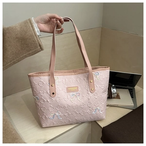 Detail of pink quilted tote bag with embroidered bow accents and embossed patterns