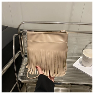 Detail of the dense long tassels on the beige PU leather crossbody bag for women
